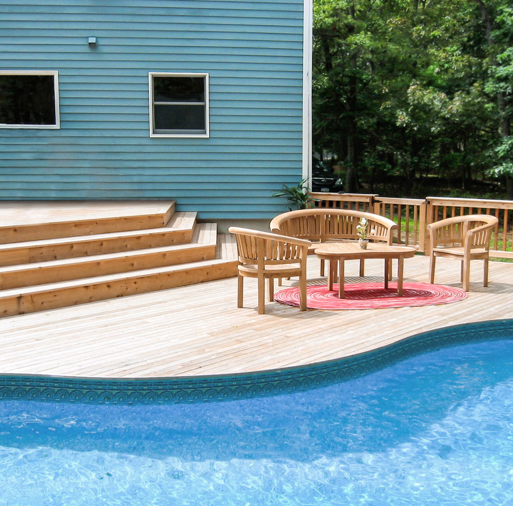 A beautifully reconstructed pool area featuring a sparkling blue pool surrounded by modern stone decking The space is enhanced with comfortable lounge chairs lush greenery and tall palm trees creating a relaxing and inviting atmosphere the pool is framed